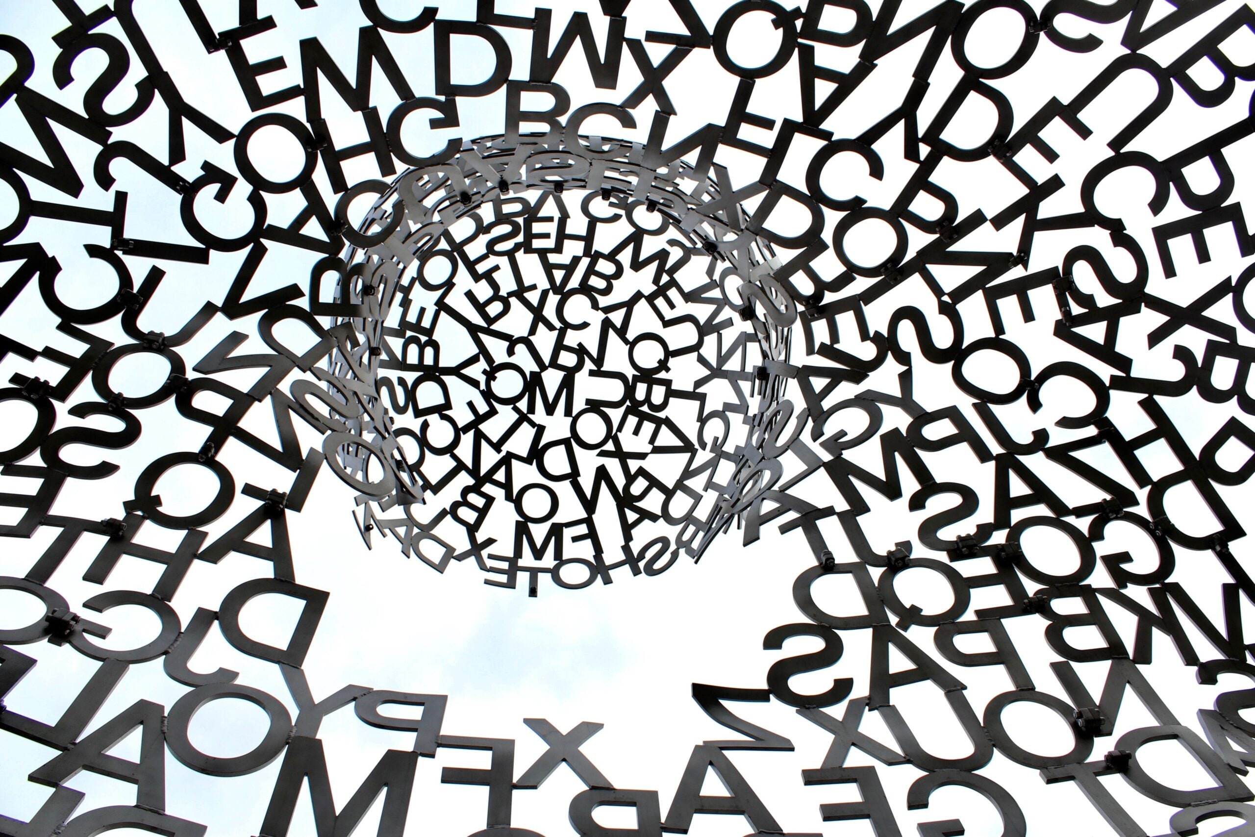 jumbled letters (black on white) coming together in the middle to form a circle but no clear meaning