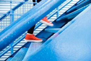 close-up of a person's feet running up a painted metal stairs