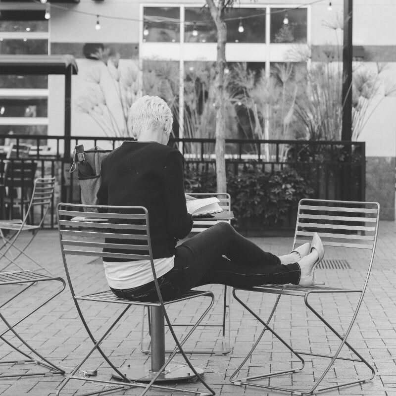 Cristen sitting at a table and writing in a public plaza